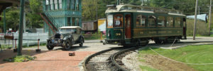 antique green trolley car and regular car